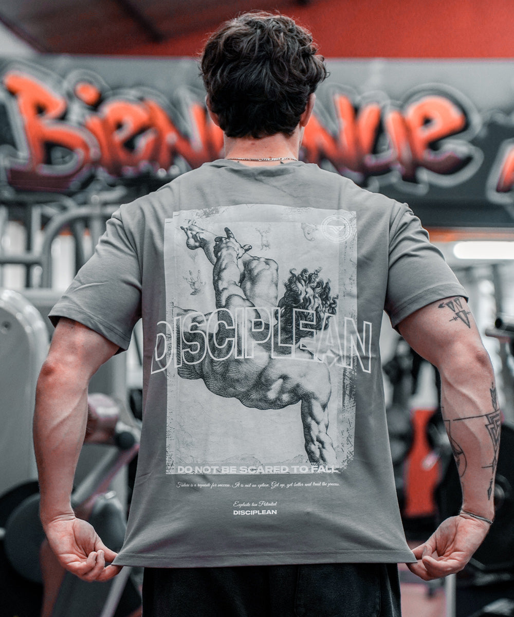 Homme de dos en salle de musculation portant un pump cover gris Disciplean