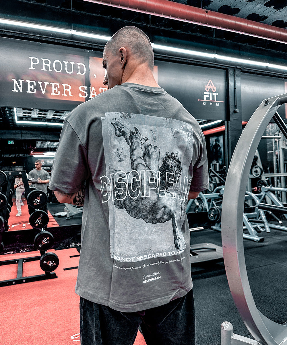 Homme de dos en salle de musculation portant un pump cover gris Disciplean