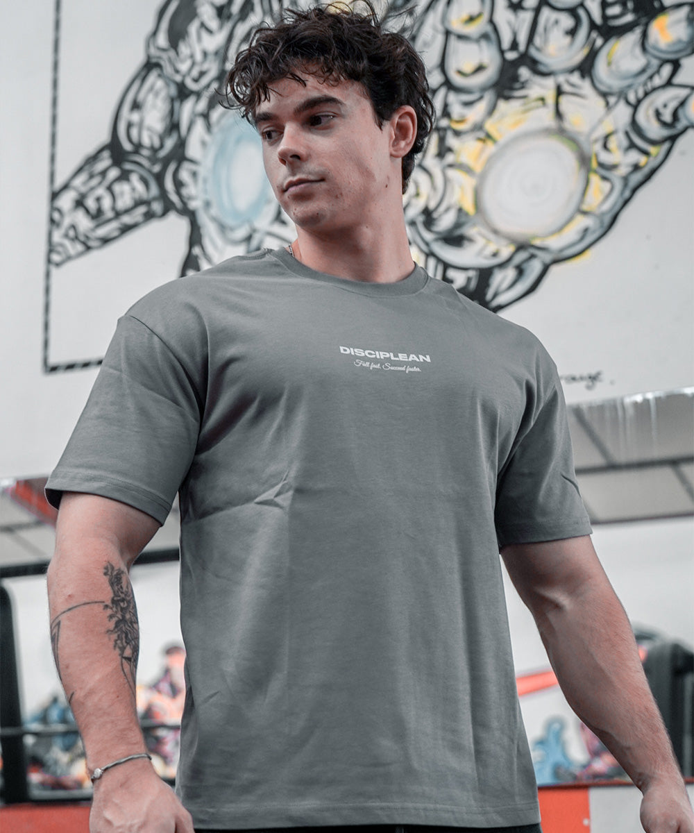 Homme de face en salle de musculation portant un pump cover gris Disciplean