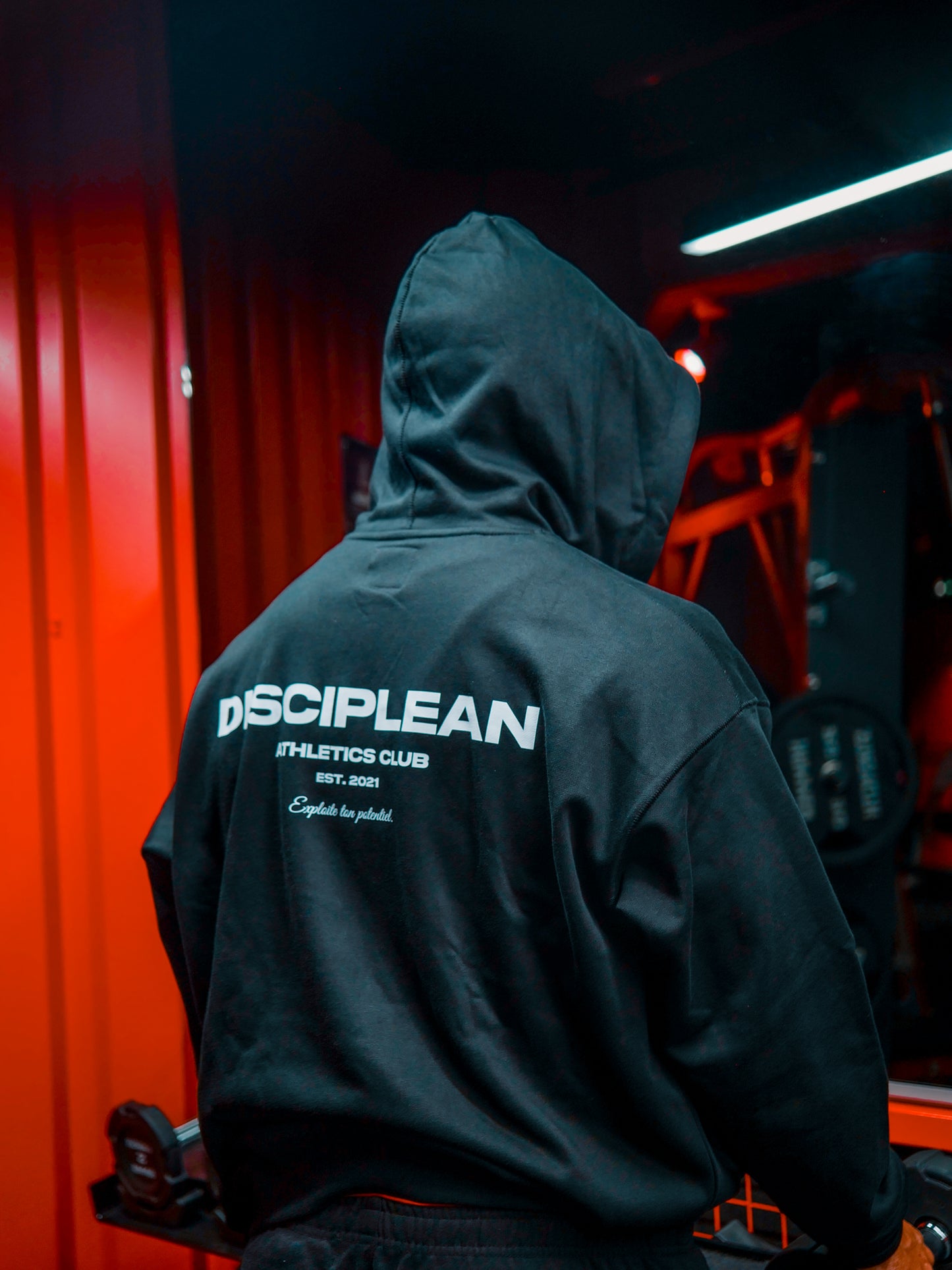 Homme de dos en salle de musculation portant un sweat avec zip noir Disciplean