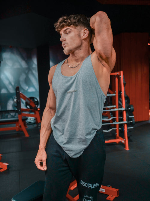Homme de face en salle de musculation portant un débardeur gris Disciplean