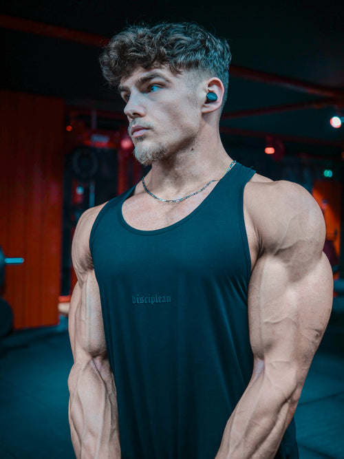Homme de face en salle de musculation portant un débardeur noir Disciplean