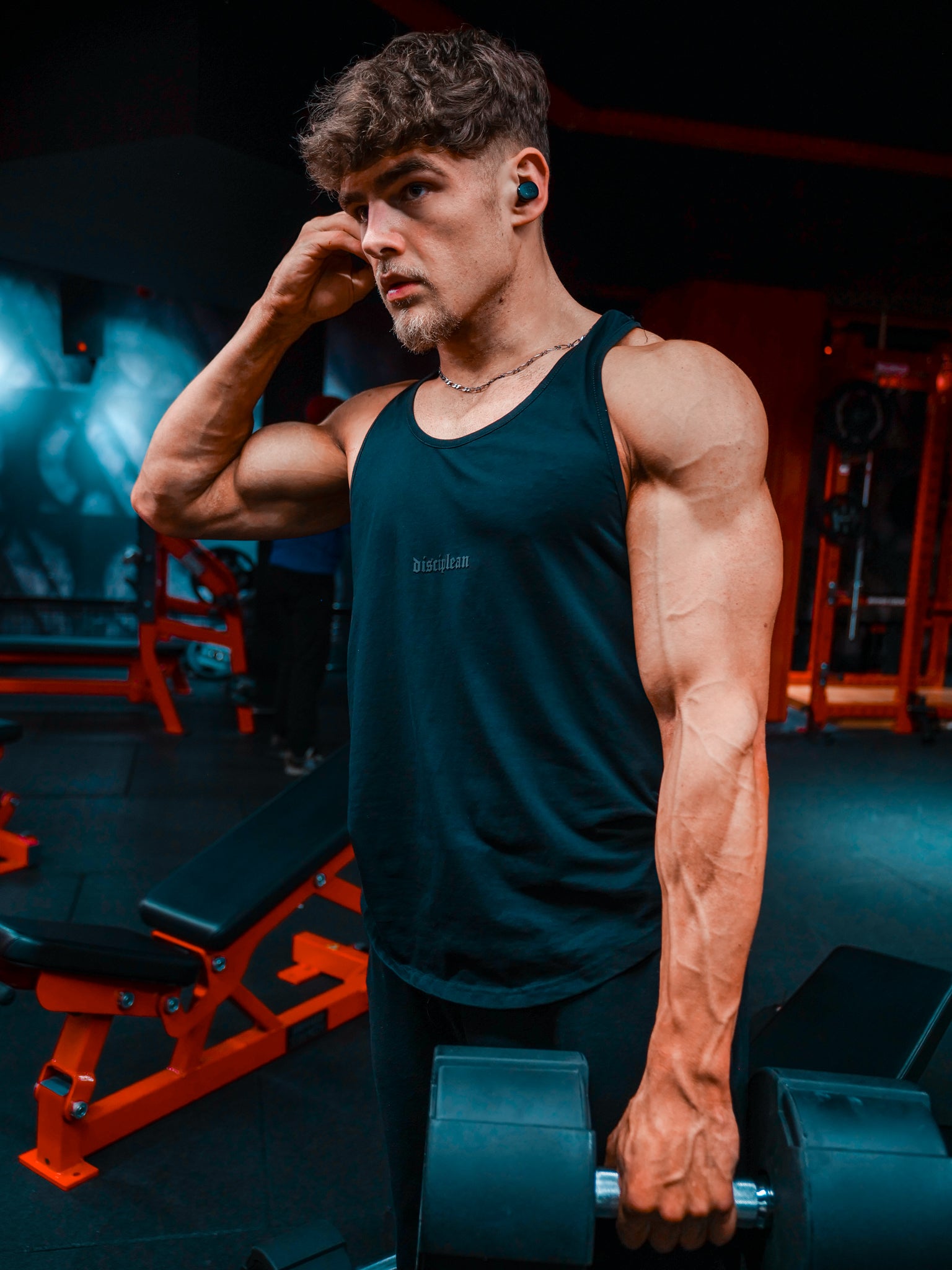 Homme de face en salle de musculation portant un débardeur noir Disciplean