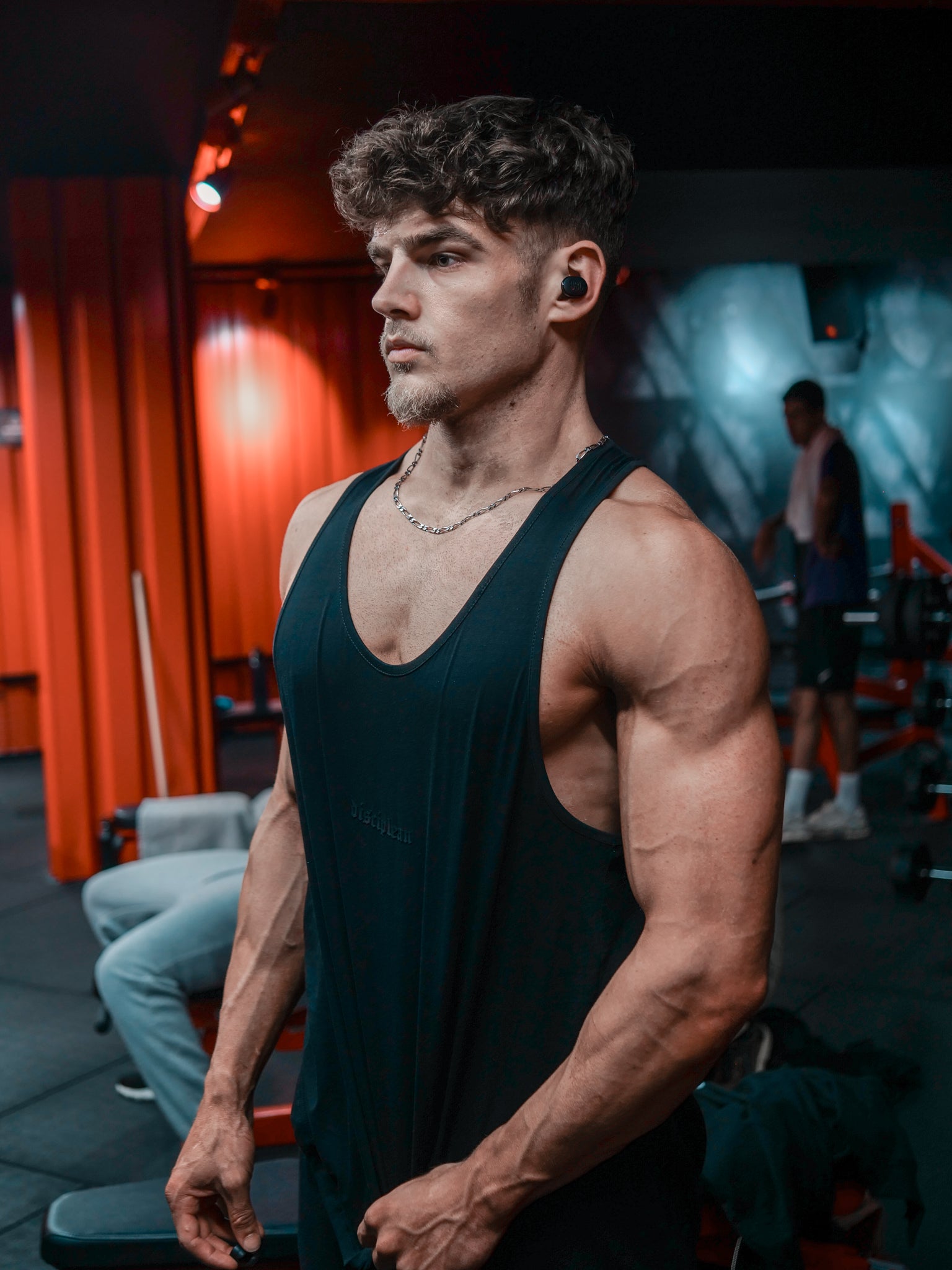 Homme de face en salle de musculation portant un débardeur noir Disciplean