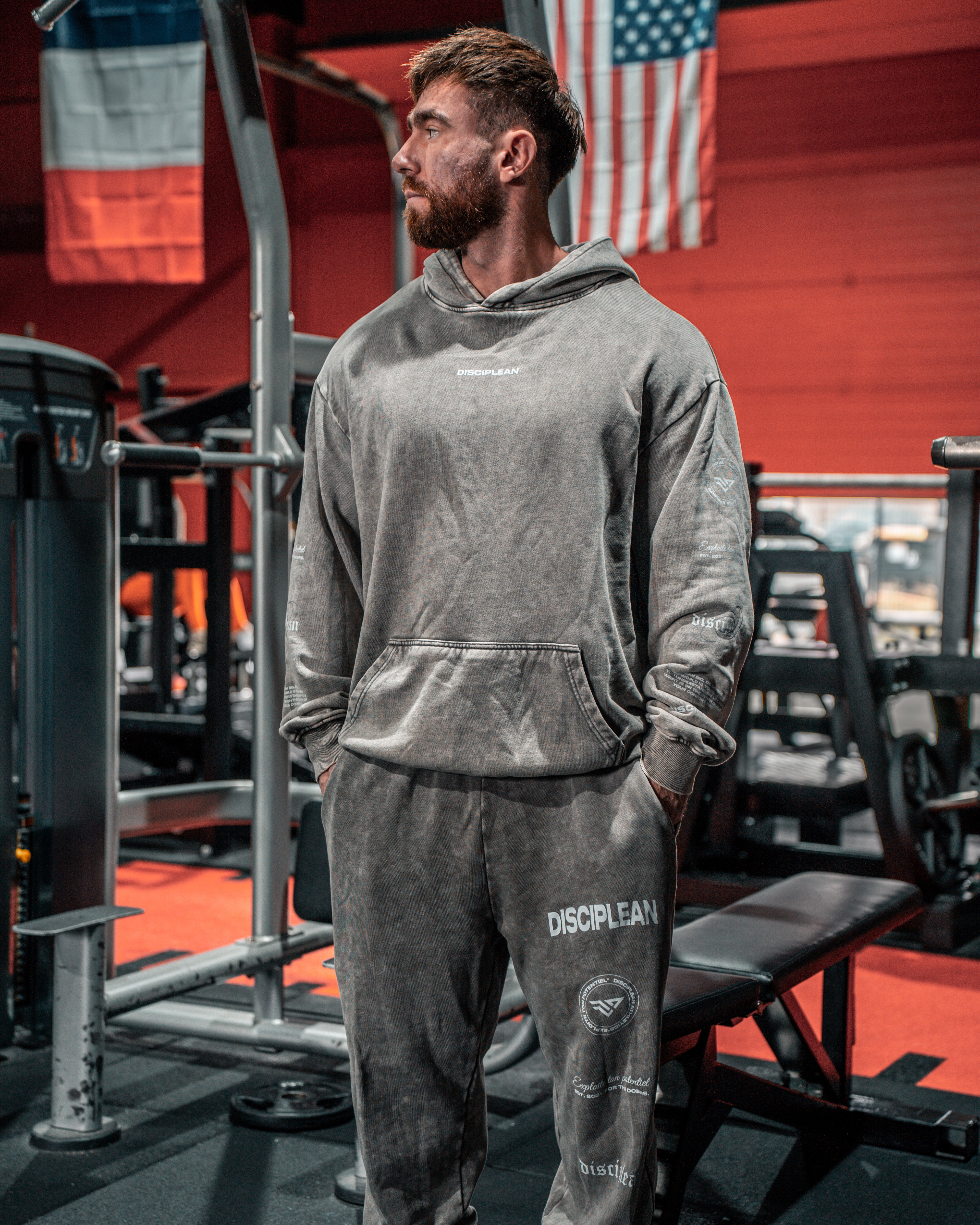 Homme de face en salle de musculation portant un hoodie et un jogging gris Disciplean