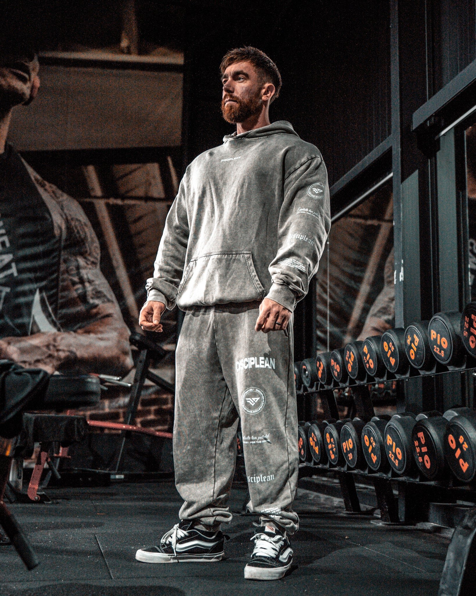 Homme de face en salle de musculation portant un hoodie et un jogging gris Disciplean