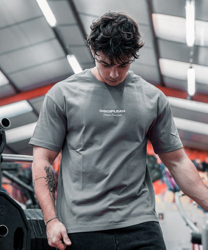 Homme de face en salle de musculation portant un pump cover gris Disciplean
